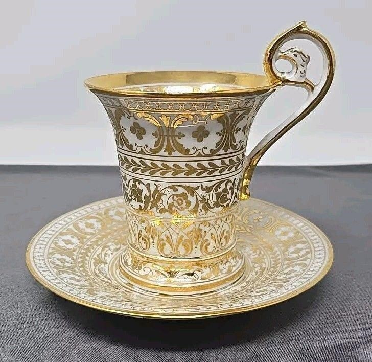 Richard Klemm Gold Demitasse Cup & Saucer: Antique Richard Klemm Dresden Porcelain Demitasse Cup & Saucer. Decorated in gold, the cup stands 4 1/8 inches tall, at the top of the handle, and 3 inches diameter. The saucer is 5 1/4 inches across.