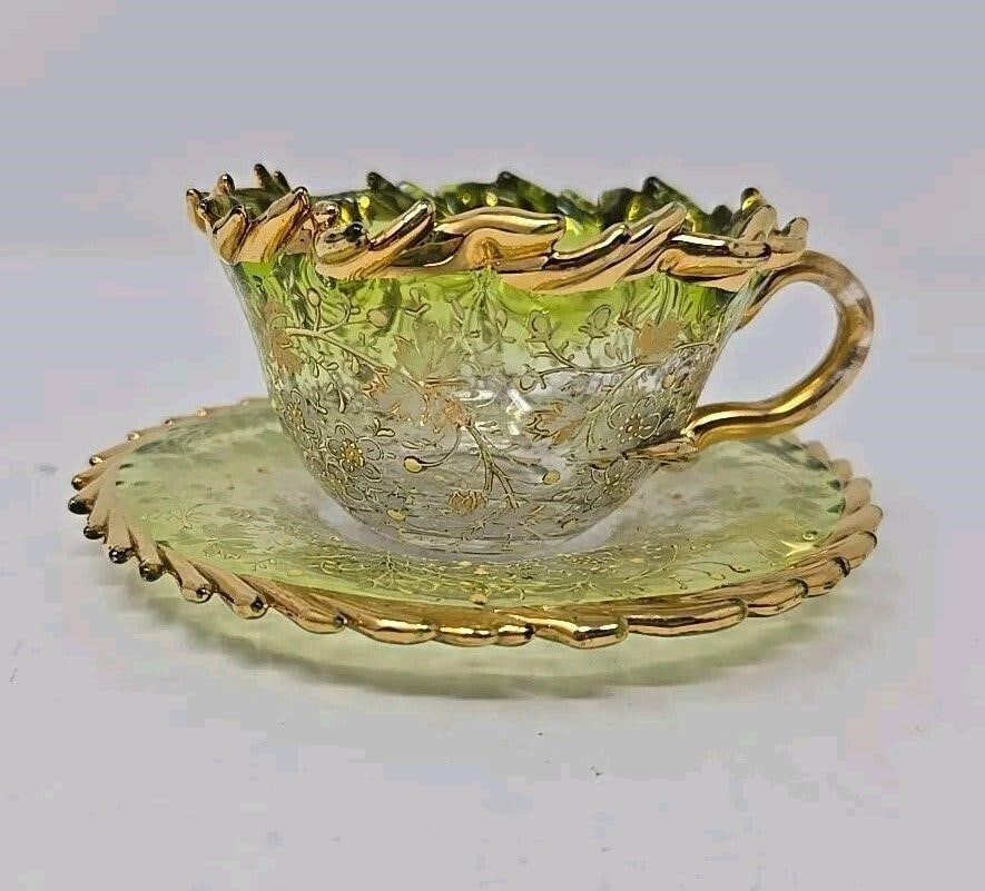 Green Fades to Clear Floral Enameled Cup & Saucer: Glass, green fades to clear Bohemian Moser style small cup and saucer set. The design is hand enameled with a floral and leaf pattern. Heavy gold ruffled rim on cup and saucer. Ground and polished
