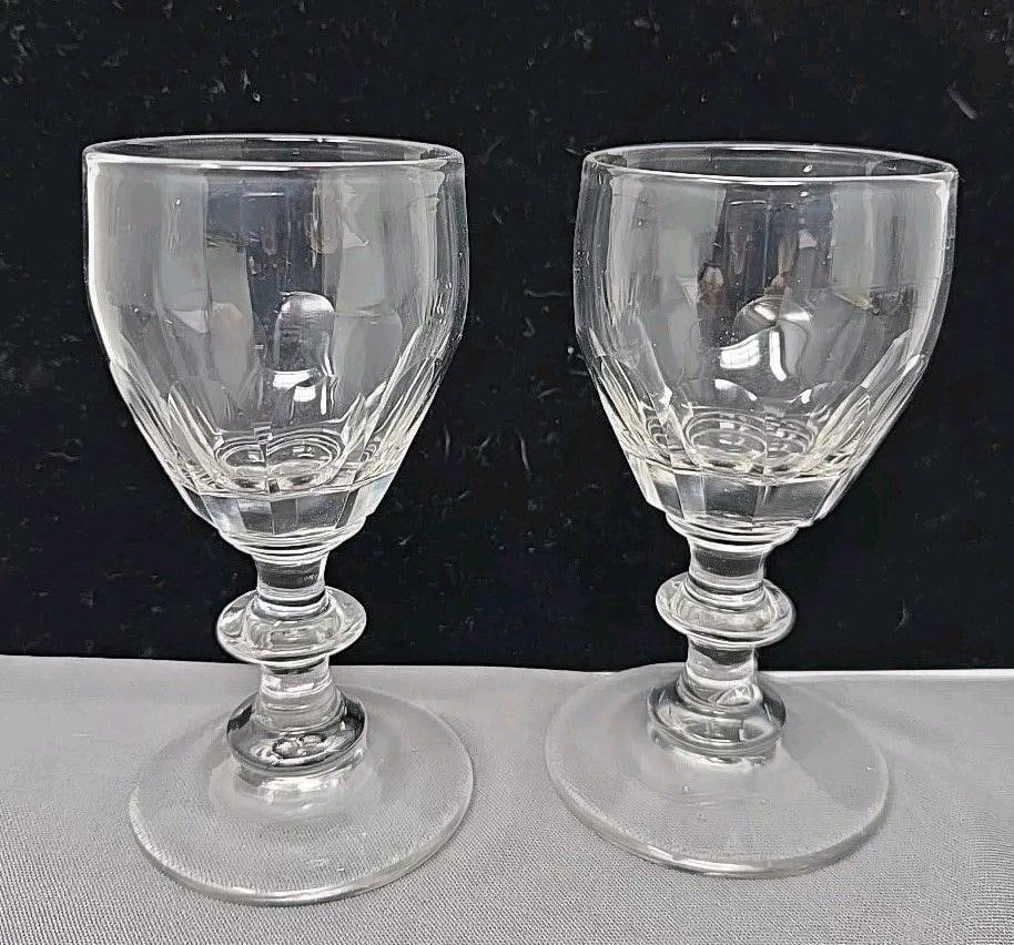 Pair Early British Georgian Flint Wine Glasses: Pair British blown flint glass cut panel small wine glasses. Ground and polished pontil. One has a pit stone on the bottom. No chips or cracks. Measures approximately 4 inches tall and 2 inch diameter