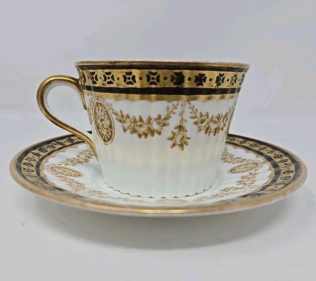 Wedgwoood Brown & Gold Tea Cup & Saucer Late 1800s: Late 1800s Wedgwood bone china cup and saucer set. There is a brown and gold floral band on edges with floral medallions and garlands on the side. Ribbed sides and a raised floral center in saucer and