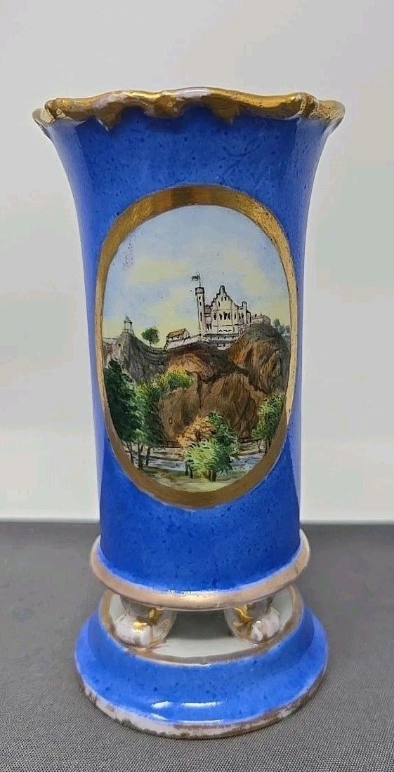 Meissen Spill Vase Oval Landscape Scenes: Meissen Footed spill vase. Two oval Landscape scenes with gold gilt on a blue background. It has 4 paw feet standing on a pedestal. It has initials on the bottom and looks as if painted on the afterma