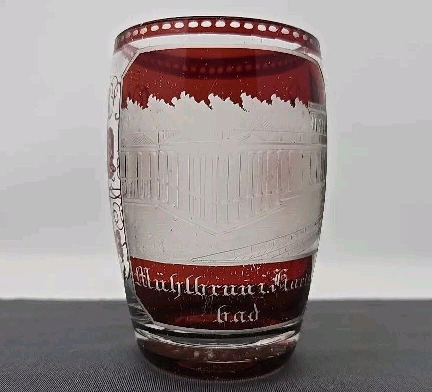 Karlsbad Bohemian Spa Souvenir Glass: Karlsbad souvenir drinking glass with ruby wash over clear glass. Etched Colonnade building , Muhlbrunnen spa. Small lip chips and scratches on ruby wash. There is a small pot stone as pictured. Late