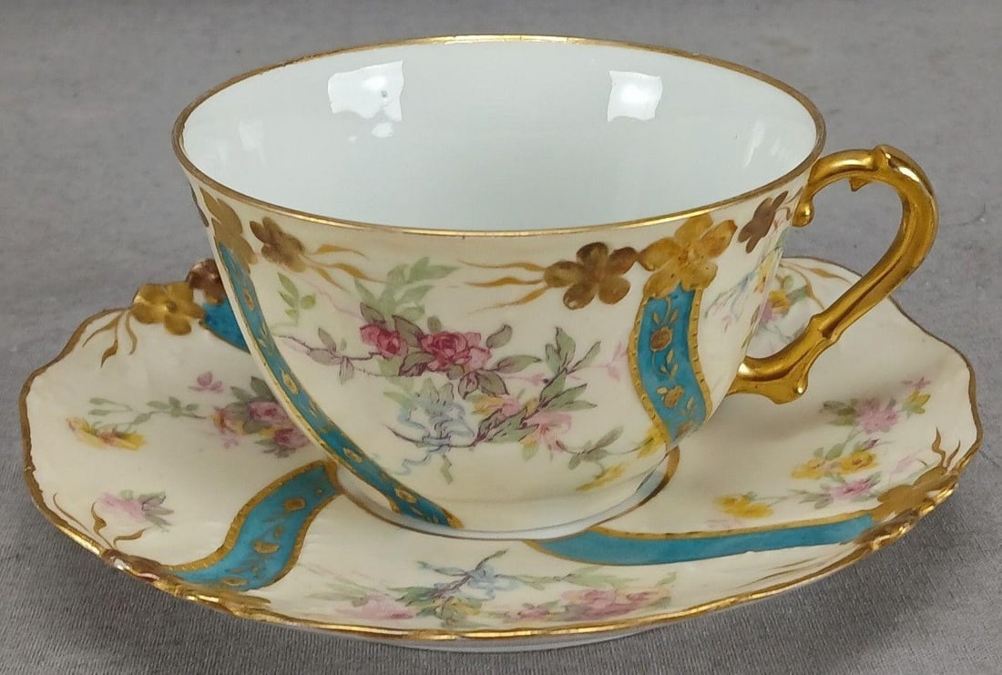 Limoges Floral Turquoise Gold Tea Cup & Saucer: Antique French porcelain tea cup and saucer with relief molded flowers with gold gilding. Decorated with pink and yellow roses over an ivory background. With turquoise panels in between. Two of the pa