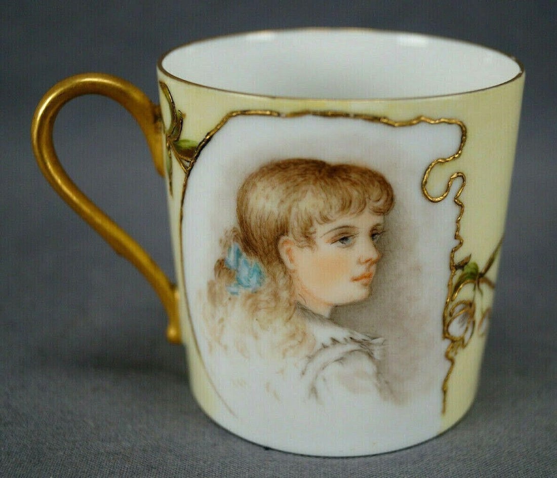 Limoges Hand Painted Lady Portrait Gold Yellow Cup: Nice antique porcelain coffee cup. Decorated with a hand painted portrait of a blonde lady with a blue bow in her hair framed by raised gold gilding and floral designs over a pale yellow background. G