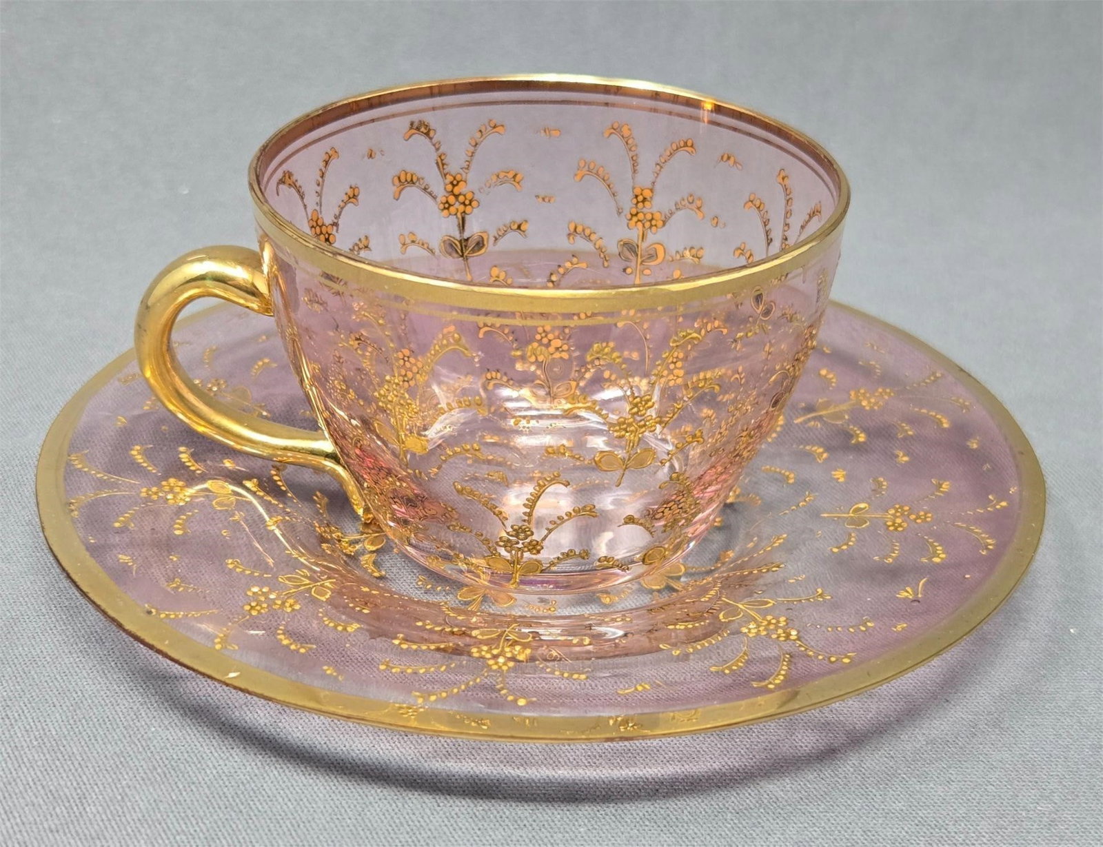 Bohemian Moser Style Demitasse Cup and Saucer: Bohemian Moser style light cranberry demitasse cup and saucer with raised gold sprigs. Polished pontils, circa 1900. Very good condition without chips or cracks or missing design. There is some light 