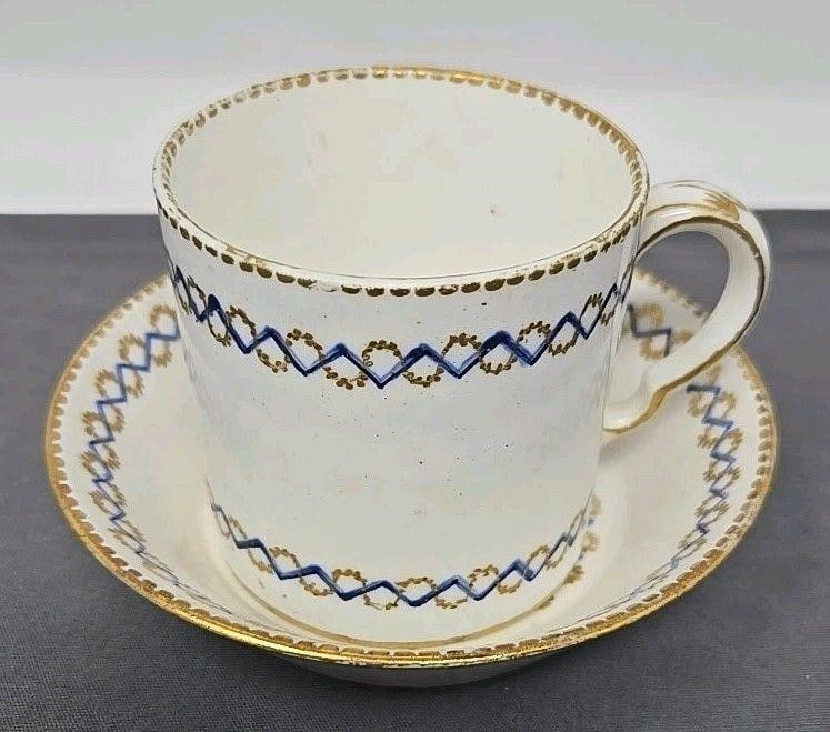 Sevres Cup and Saucer Blue And Gold Bands C. 1785: Antique Sevres cup and saucer set. It has blue and gold interwoven bands and a gold gilt scalloped edge. Circa 1785, it has the date code HH. It has a painter mark of 3 dots that are underlined for Vi