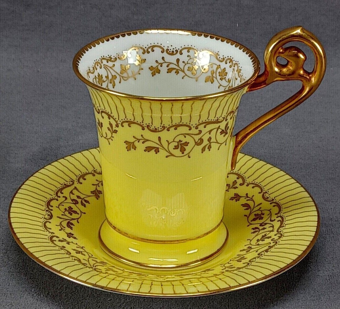 Cauldon Yellow & Gold Chocolate Cup & Saucer B: Nice antique empire form bone china chocolate cup and saucer. Decorated with a gold gilt floral scrollwork pattern over a yellow background. Gold gilt floral scrollwork pattern over white on the insid
