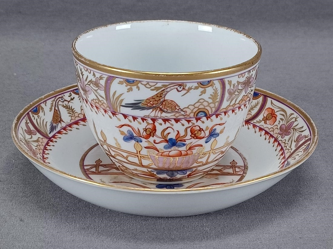 Spode Floral Basket & Birds Tea Cup & Saucer: Nice antique British bone china tea cup and saucer. Decorated in Spode's pattern 498 with hand painted flowers, birds, and flower basket in a pale purple, blue, red, and gold. Gold gilding along the e