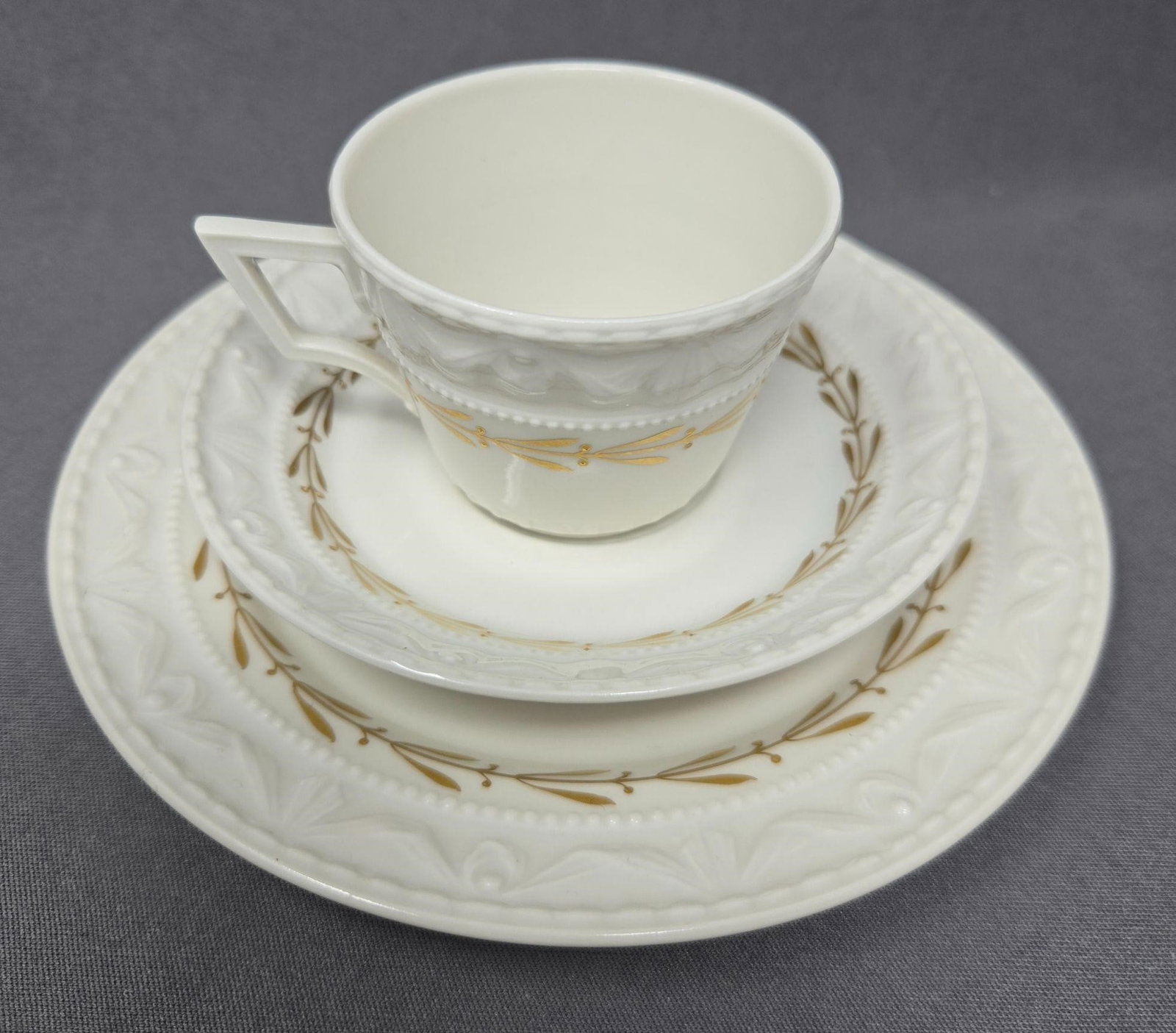 KPM Demitasse Cup and Saucer Tri0 Gold Laurel: KPM red mark porcelain trio with demitasse / mocha cup, saucer and dessert plate. Circa 1880. Painted gold laurel band pattern on rim. Marked 518. Very good condition without chips or cracks or scratc