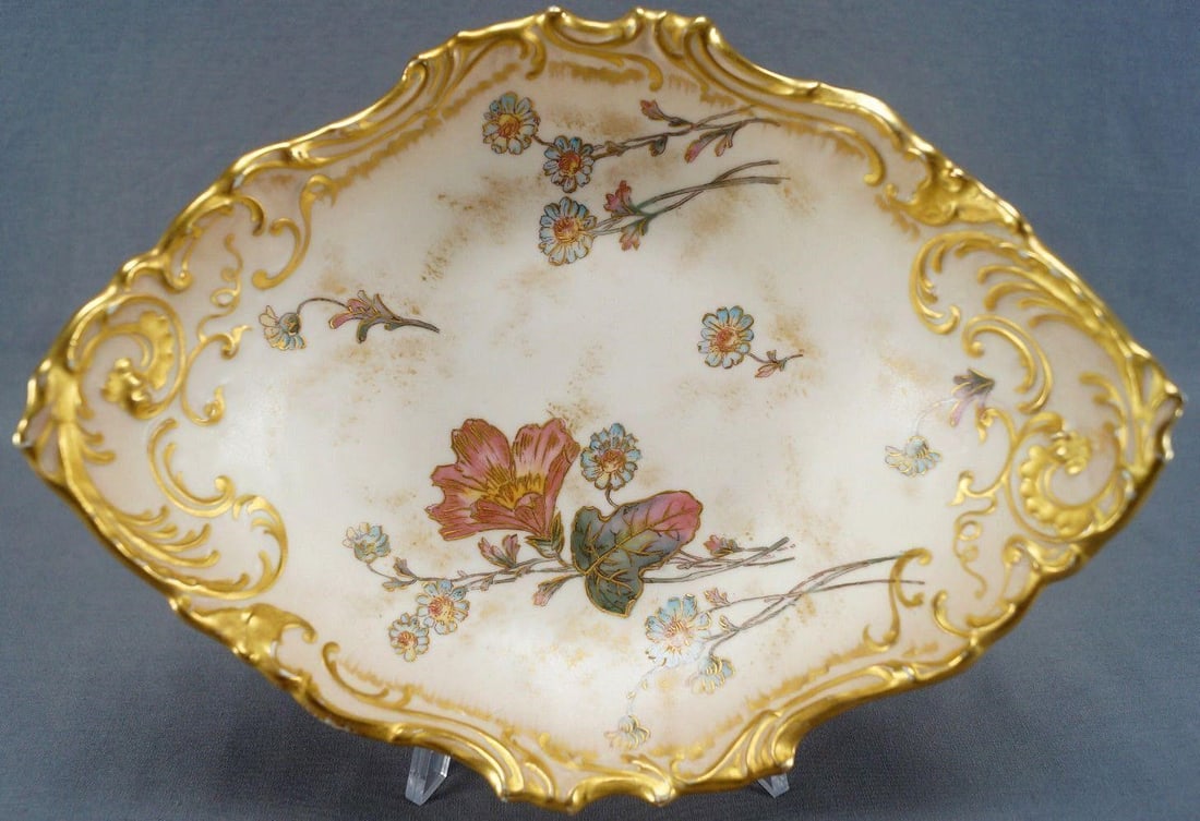 Limoges Floral & Gold Blush Ivory Centerpiece Bowl: Pretty porcelain centerpiece bowl with heavy relief molded and gilded scrollwork designs along the edge. Decorated with hand colored pink and blue flowers with raised gold gilt highlights over an