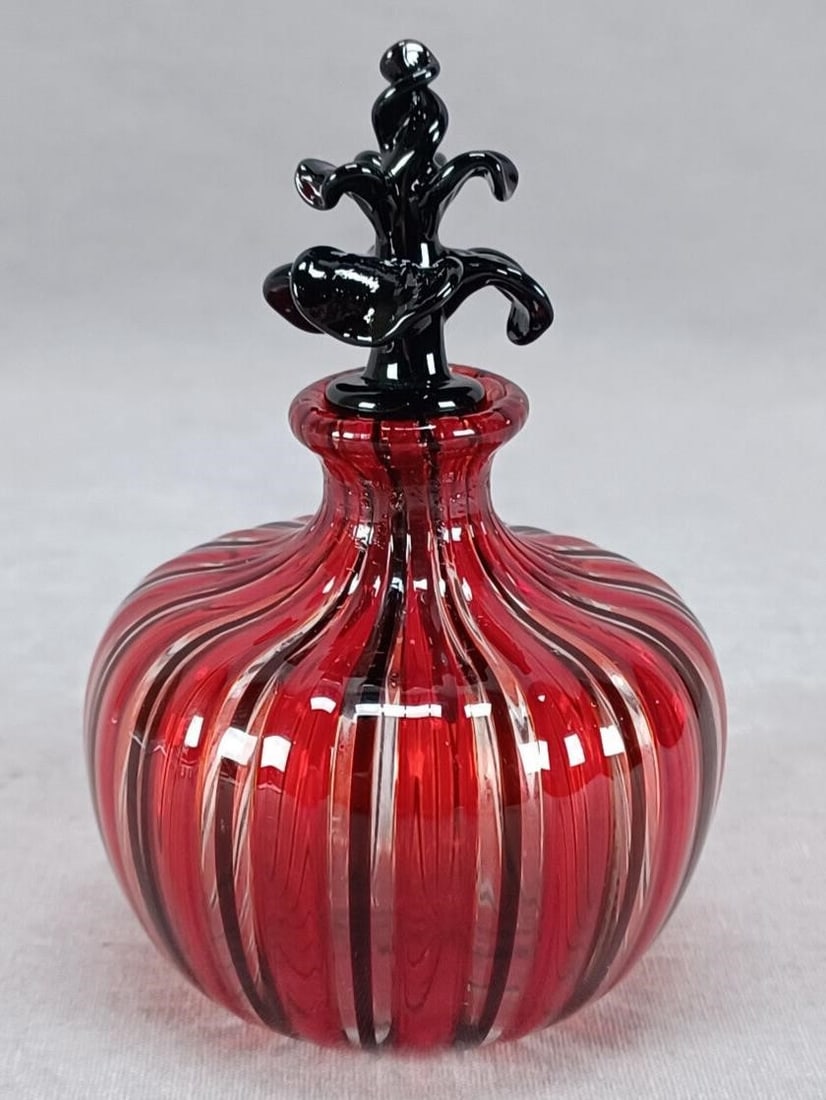 Italian Murano Cenedese Vetri Perfume Bottle: Nice vintage Italian Murano Cenedese Vetri blown glass perfume bottle in a Filigrana pattern in red, clear, and black. Black glass stopper. Rough pontiled base.Good condition.Measures approximately 2 