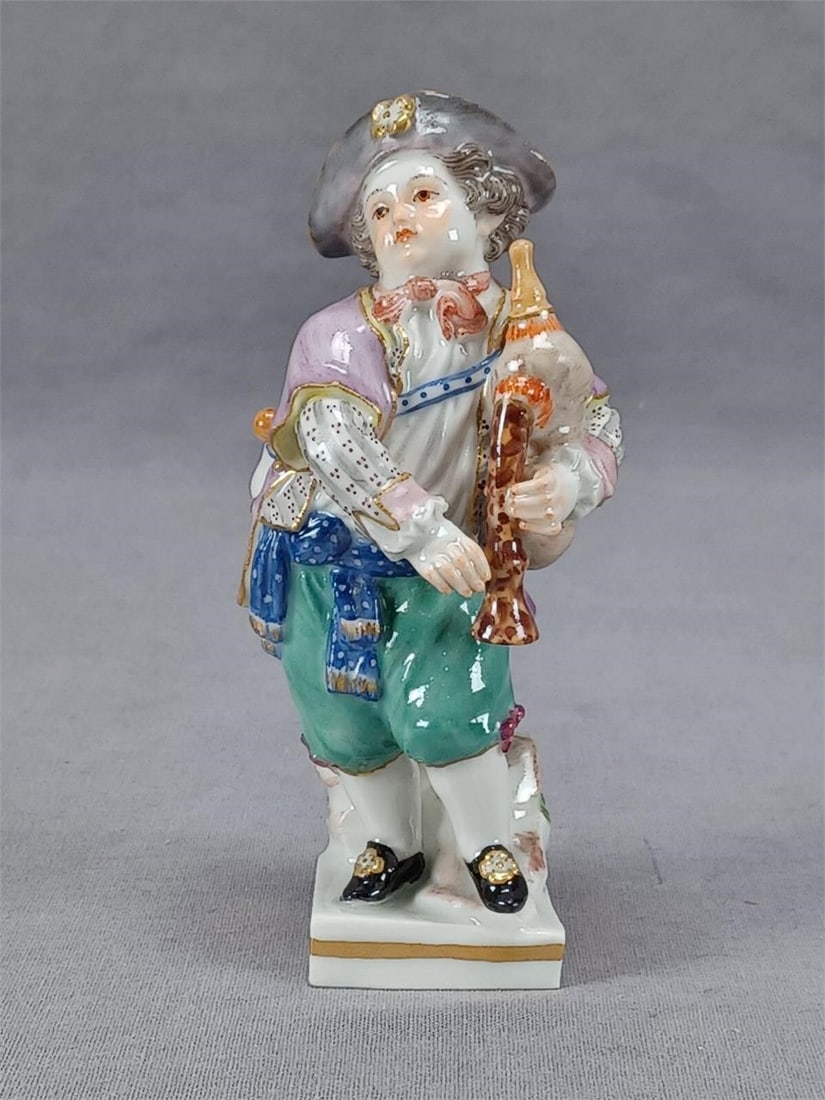 Meissen G11 Boy With Bagpipes Figurine C 1870-1880: Very nice porcelain G11 Boy with bagpipes figurine. Hand painted with a grey hat with gold gilding, purple jacket, and green pants. With gold gilding along the base. Marked on the bottom with the blue