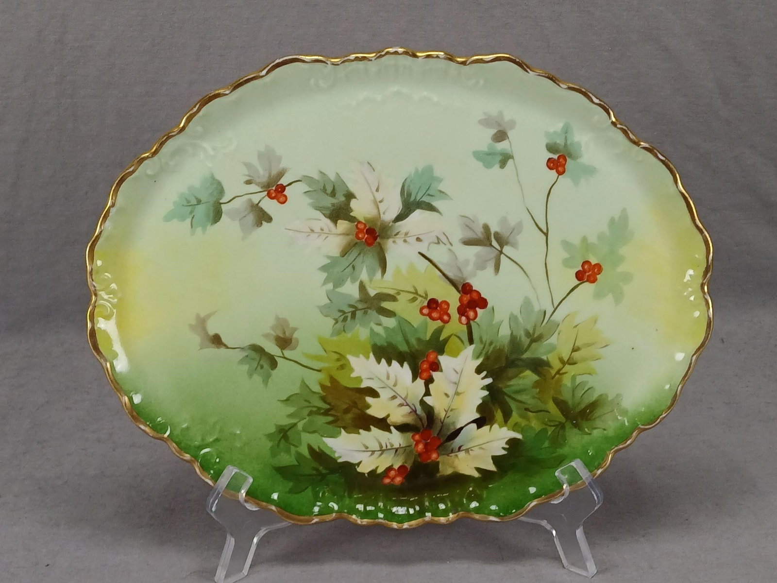 Limoges Hand Painted Holly Berries Dresser Tray: Antique French porcelain dresser tray with relief molded scrollwork along the edge. Decorated with hand painted red holly berries and leaves over a green and yellow background. Gold gilding along the 