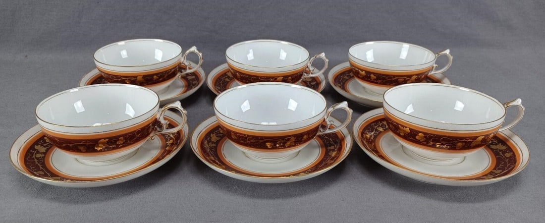 6 Fischer & Mieg Grapevine Tea Cups & Saucers: Nice set of 6 late 19th century Austrian / Bohemian porcelain tea cups and saucer. Decorated with a brown and orange band with gold gilt grapevine overlay. Unmarked. Produced by Fischer & Mieg Pirkenh