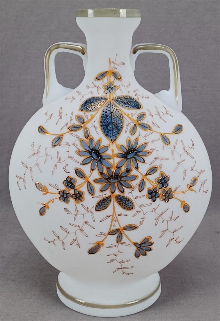 Harrach Enameled Floral White Satin Glass Vase: Nice antique Bohemian white satin glass vase. Decorated with hand enameled blue, black, yellow ocher, and gold flowers. Green and gold trim along the opening, handles, and around the foot rim. Unmarke