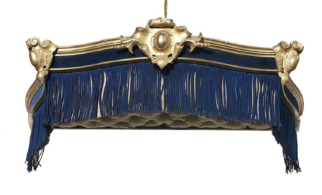 French Giltwood Cornice: French Giltwood Cornice 19th century, the molded crest centered by a shield carving with like corner accents, over a fabric frieze and a fringe apron, the interior tufted and padded. h. 9", w. 57", d.