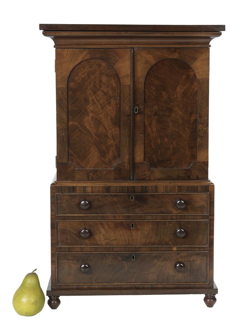 William IV Miniature Mahogany Linen Press: William IV Miniature Mahogany Linen Press second quarter 19th century, the two-piece linen press with arched door panels, turned knobs and turnip feet, the drawers with original blue paper linings. h.