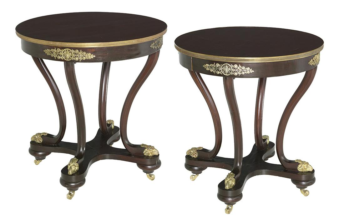 Pair of Empire Mahogany Center Tables: Pair of Empire Mahogany Center Tables 19th century, each with a circular top within an ormolu band, raised above an ormolu-applied frieze on four shaped supports ending in ram's-head sabots, on a quad