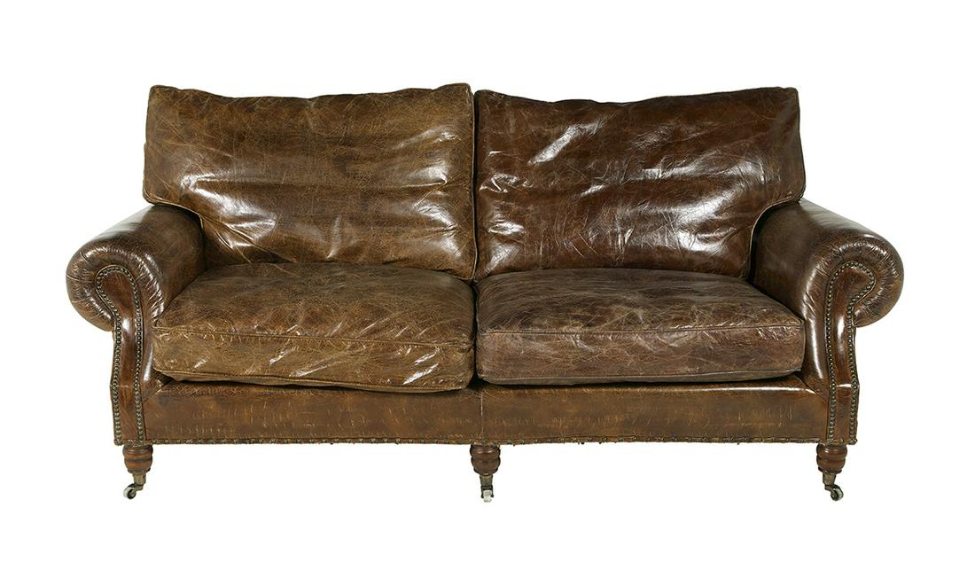 Edwardian-Style Leather Sofa: Edwardian-Style Leather Sofa the back and seat each with a pair of loose cushions, the closed arms of baluster form, their supports and apron edged with brass tacks, raised on turned legs with cup cas