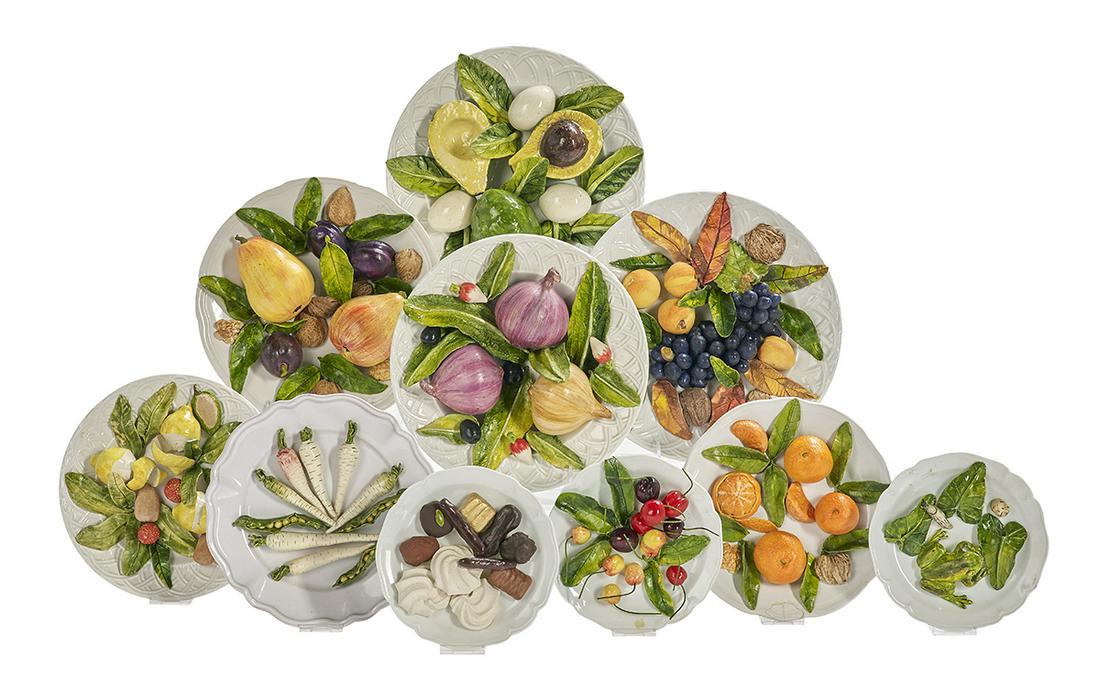 Christine Viennet (Franco-Norwegian, b. 1947): Ten Epicurean Ceramic Sculptures by Christine Viennet (Franco-Norwegian, b. 1947) the collection including plates depicting various fruits and vegetables, nuts, eggs, peeled lemons, chocolates, mering