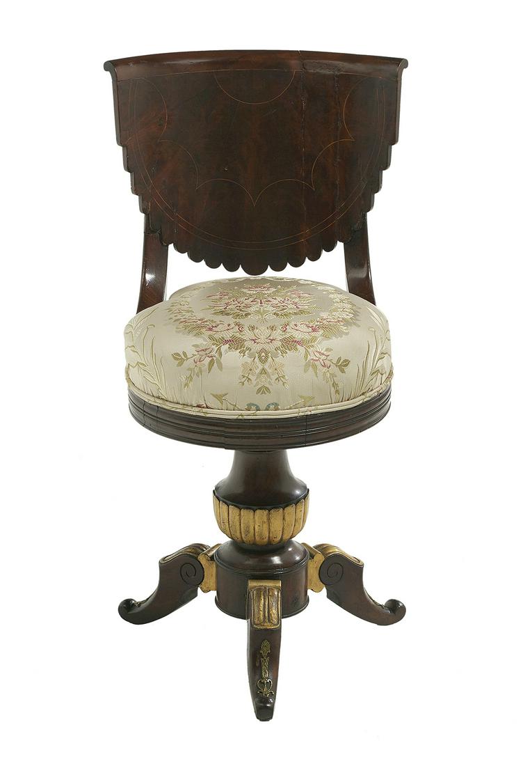 Empire Parcel-Gilt Mahogany Swivel Piano Chair: Empire Parcel-Gilt Mahogany Swivel Piano Chair second quarter 19th century, the curved back with fan veneers and string inlay, and down-curved supports joining the seat, and mounted to a turned and ca