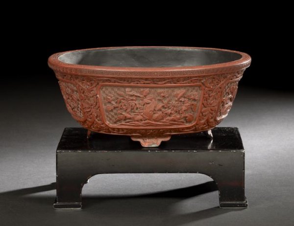 Chinese Carved Cinnabar Lacquer Planter: Chinese Carved Cinnabar Lacquer Planter, Daoguang Reign (1821-1850), of oval outline and resting on four shaped feet, the lacquer carved with four reserve panels of flowers around the body against a g