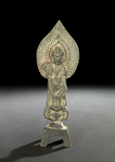 Chinese Bronze Figure of a Buddhist Deity: Chinese Bronze Votive Figure of a Buddhist Deity, Tang Dynasty (618-907), the cast-bronze figure dressed in Indian-style robes with a flaming mandorla, one hand raised in blessing, standing on a four-