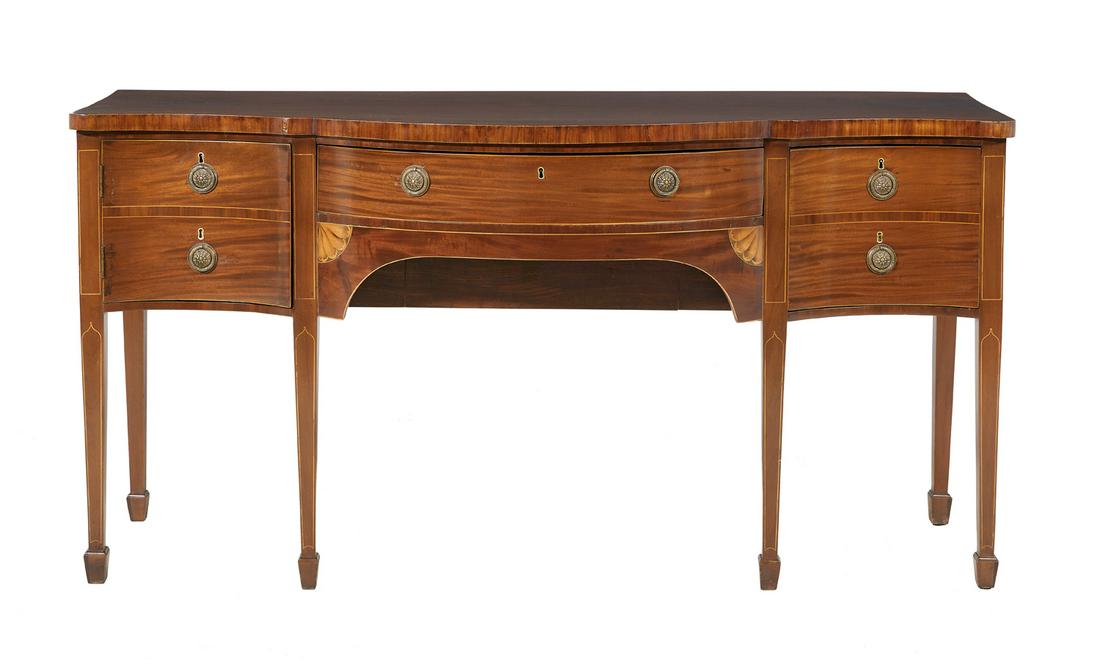 George III Mahogany Sideboard: George III Mahogany Sideboard fourth quarter 18th century, with a shaped and bowed top above a fitted central drawer, flanked to one side by a cupboard and to the other by a deep drawer, both faced as