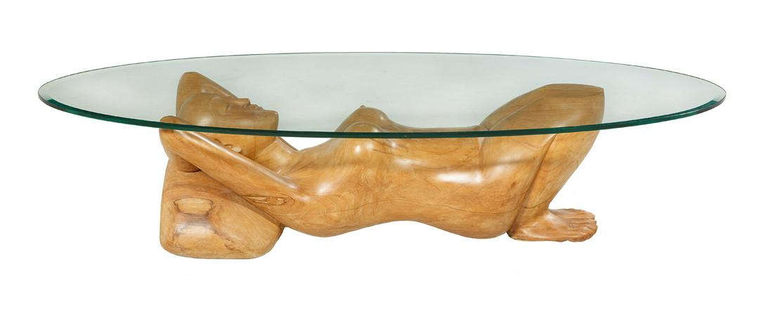 Mango Wood and Glass Figural Coffee Table: Carved Mango Wood and Plate-Glass Figural Coffee Table mid-20th century, with an oval beveled glass top, the carved base in the form of a nude woman in the supine position, her head resting on a pillo