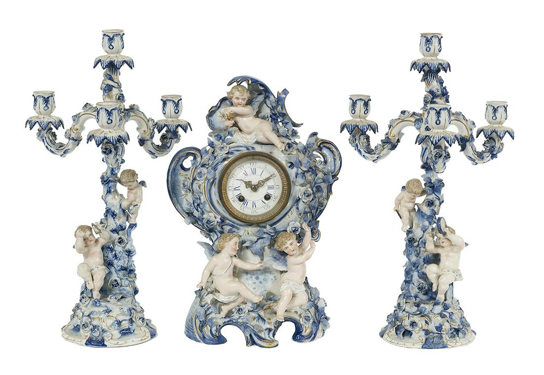Three-Piece Dresden-Style Clock Set: Three-Piece Dresden-Style Clock Set fourth quarter 19th century, German, the set with cobalt trim and decorated with porcelain cupids and encrusted flowers, comprised of a clock, h. 15-1/2", w. 9-1/2"