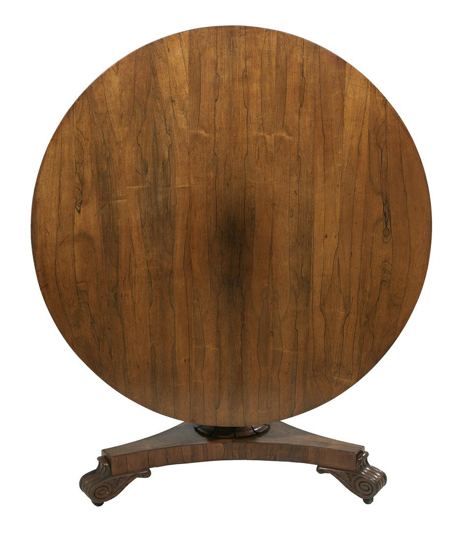 Late Regency Rosewood Center Table: Late Regency Rosewood Center Table second quarter 19th century, the circular tilting top raised on a foliate-carved columnar standard to a concave tripartite base to scrolling feet on casters. h. 29",