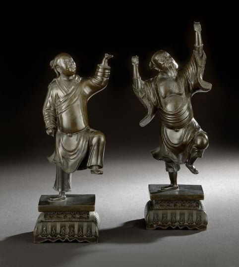 Two Chinese Bronze Figures of Acrobats: Two Chinese Bronze Figures of Acrobats, 19th century, each dressed in coats and trousers and posed in action stances, mounted on square bases above engraved curtain feet, h. 11-1/4" and 13".