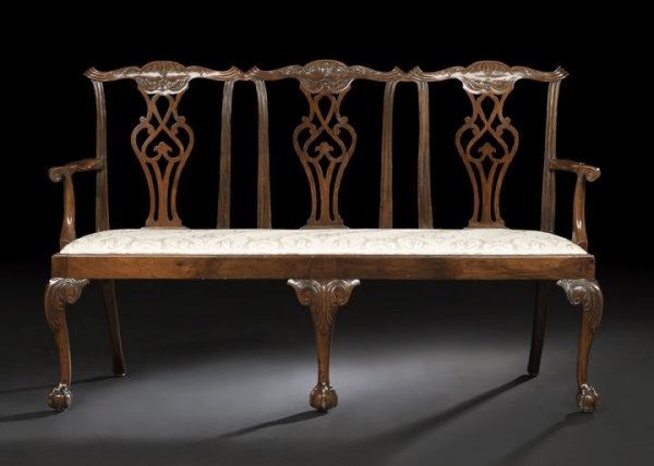 George III Mahogany Settee: George III Mahogany Settee, 19th century, the triple chairback with a shaped foliate-carved crest above three pierced baluster-form splats, joined to the padded seat by outscrolled arms, raised on cab