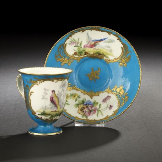 Fine Sevres Porcelain Chocolate Cup and Saucer: Fine Sevres Porcelain Chocolate Cup and Saucer, ca. 1775, having bleu-celeste grounds with gold-framed avian reserves, the footed cup of beaker form, with the underglaze blue entwined L's mark of Sevr