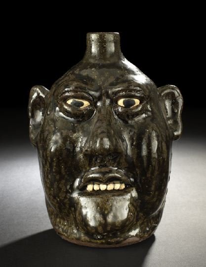 Lanier Meaders Tobacco-Spit-Glazed Pottery Jug: Good Lanier Meaders Tobacco-Spit-Glazed Pottery Jug, ca. 1980, in "Character Mask" decor, the irises and the teeth glazed in off white, signed on the base in incised script, h. 8-1/2", w. 6-3/4".