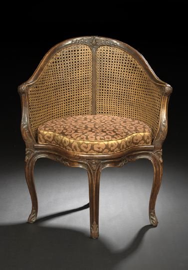 Provincial Louis XV-Style Bergere en Encoignure: Provincial Louis XV-Style Fruitwood Bergere en Encoignure, third quarter 19th century, the domed and bisected caned back surmounted by a floral crest and joined to the cushioned caned seat by downswep