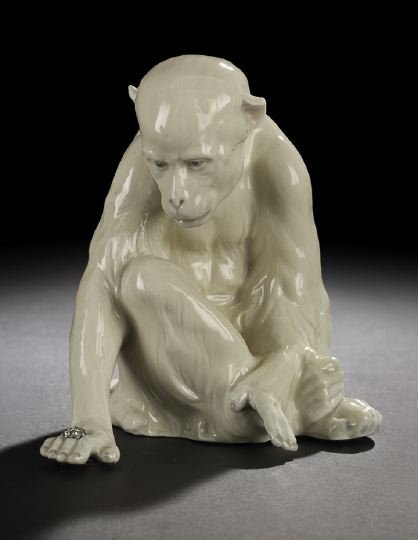 Continental Glazed Porcelain Figure of a Monkey: Amusing Continental Glazed Porcelain Figure of a Monkey, third quarter 20th century, the seated primate admiring a purloined "diamond" ring on its hand, the glazing in off-white and gray, h. 5-3/4".