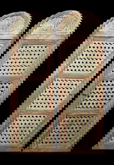 Pair of North African Carved Arch-Top Doors: Pair of North African Carved Wooden Arch-Top Doors, first quarter 20th century, of tall size in the traditional style, each door carved, pierced and wrought-iron mounted, and bearing traces of old wea