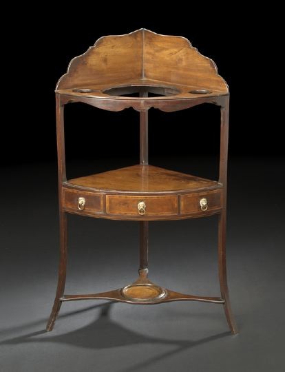 American Federal Mahogany Corner Washstand: American Federal Mahogany Corner Washstand, ca. 1800, in the Hepplewhite taste, the scalloped gallery joined to a top with a cut-out for a washbasin, the medial bowfront shelf fitted with a single dra