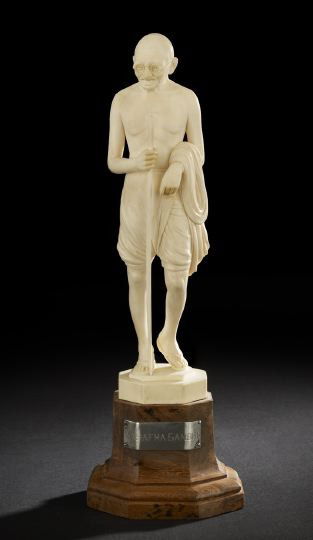 Japanese Ivory Okimono of Mahatma Gandhi: Japanese Ivory Okimono of Mahatma Gandhi, 20th century, the carved ivory statue depicting the peace advocate standing with a staff wearing glasses and his scant garment with sandals, presented on a wo