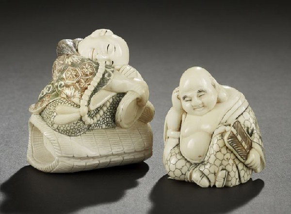 Two Japanese Carved Ivory Statues: Two Japanese Carved Ivory Statues, comprised of a carving of the Happy Buddha seated with his fan and with inked details, and a larger carving of a boy in a brocade robe sleeping atop a woven bundle w