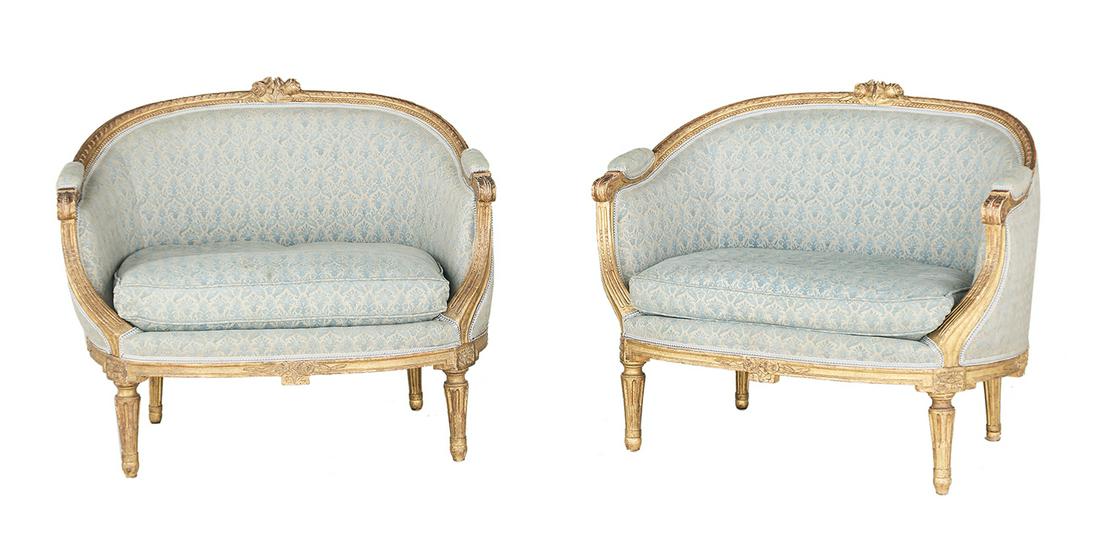Pair of Louis XVI-Style Giltwood Low Bergeres: Pair of Louis XVI-Style Giltwood Low Bergeres early 20th century, each with a low padded back surmounted by a floral crest, joined by downswept sides to the cushioned seat, raised on stop-fluted taper