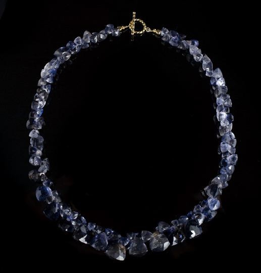 Graduated Natural Iolite Necklace: Graduated Natural Iolite Necklace, the single strand composed of faceted pyramidal beads with larger beads at the front, with a gold-tone hoop and bar clasp, l. 17".