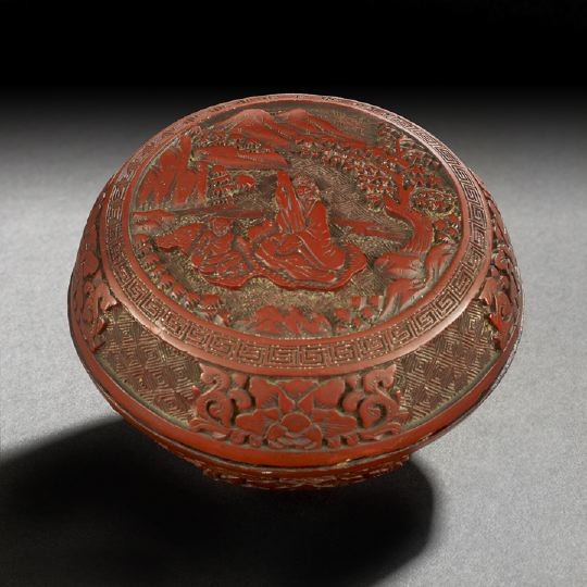 Chinese Carved Cinnabar Lacquer Box: Chinese Carved Cinnabar Lacquer Box, 19th century, of circular outline carved on the cover with the seated figure of a woman playing music to a young child in a mountainous landscape surround, the cov