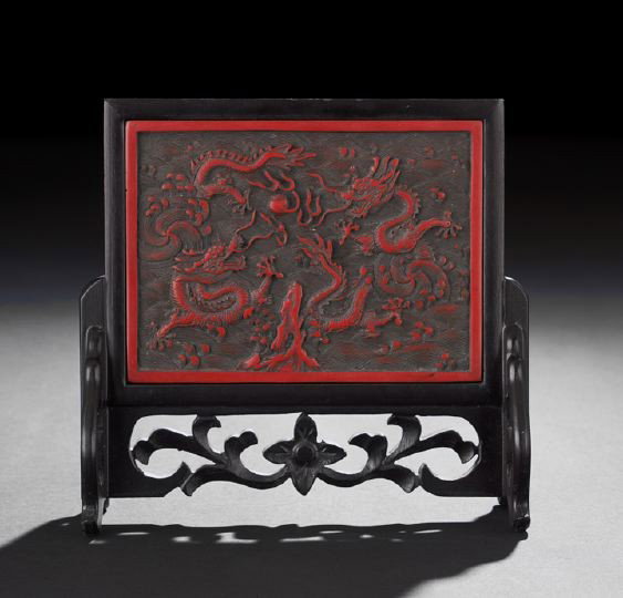 Chinese Carved Cinnabar Lacquer Table Screen: Chinese Carved Cinnabar Lacquer Table Screen, late Qing Dynasty, mounted in an integral wooden stand, the reverse with a calligraphic inscription, the screen carved in low relief depicting two Imperia