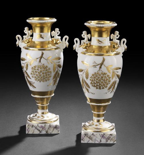 Pair of Gold and White Porcelain Garniture Vases: Pair of Continental Gold and White Porcelain Garniture Vases, first quarter 19th century, the elaborate handles featuring cherubs astride swans, the bodies decorated with baskets of wheat on one side 