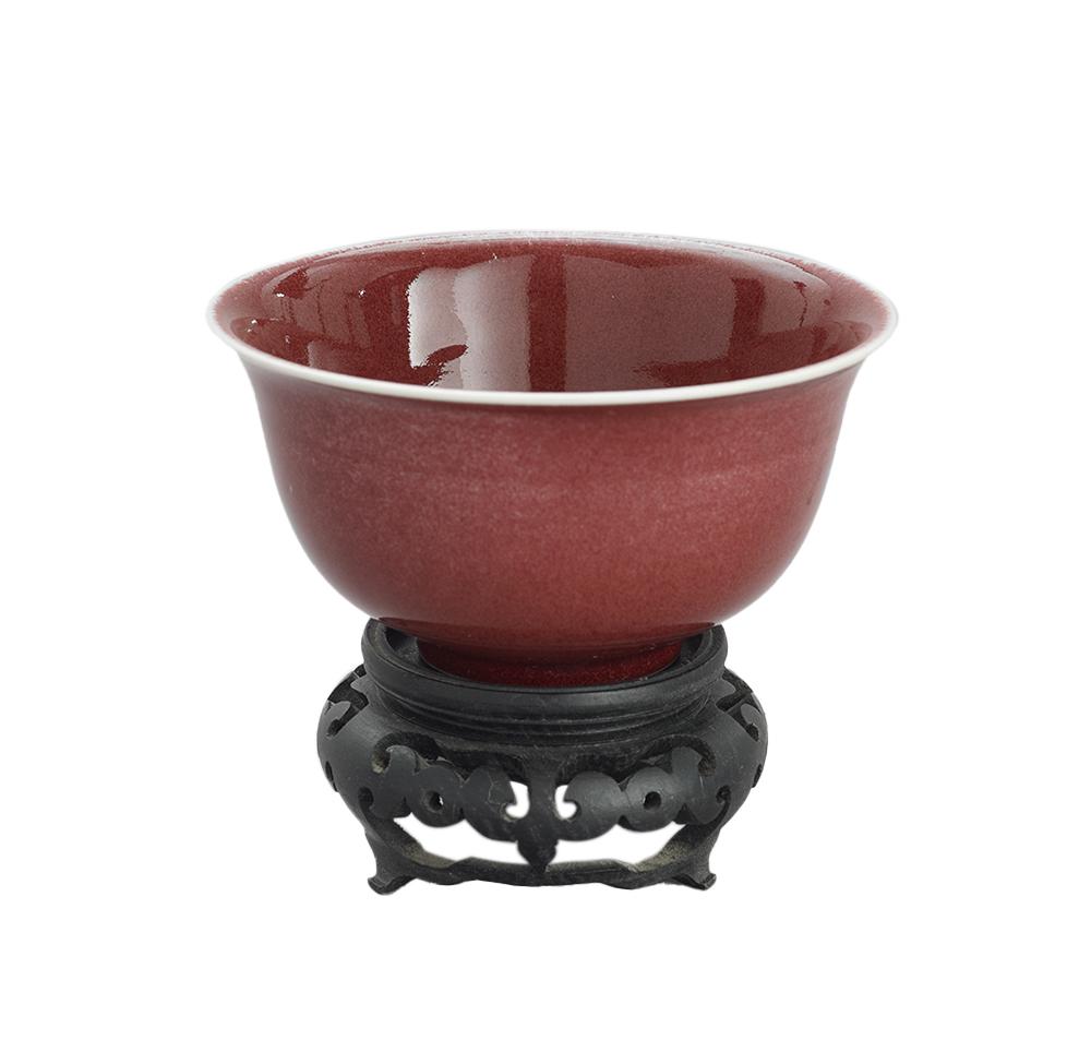 Chinese Sang de Boeuf Bowl on Stand: Chinese Sang de Boeuf Bowl on Stand 20th century, the glazed red bowl with two blue concentric circles on the underside, displayed on a carved wooden stand. bowl h. 2-3/4", dia. 5-1/4"