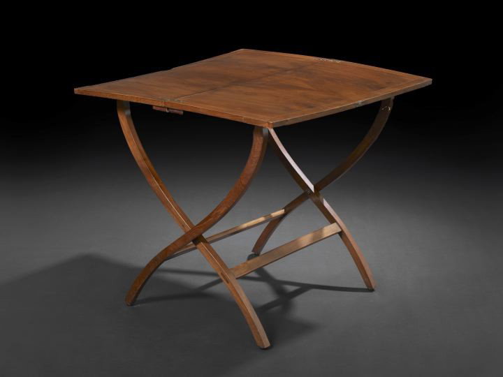Edwardian Mahogany Campaign Coaching Table: Edwardian Mahogany Campaign Coaching Table, ca. 1900, the rectangular top bisected and hinged to fold doen, railed on a curule-form supports, h. 27-1/4", w. 30", d. 29-1/2". A similar example is illus