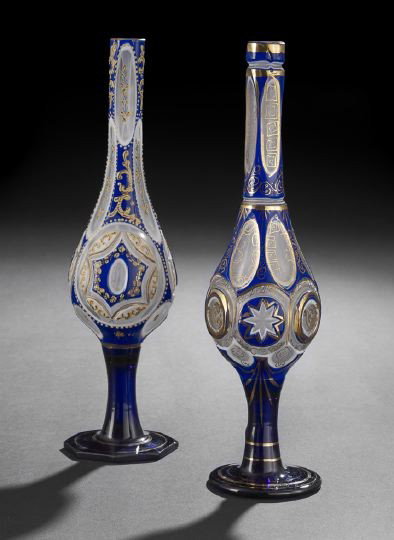 Two Bohemian Glass Rosewater Bottles: Two Bohemian Glass Rosewater Bottles, first quarter 20th century, of Middle Eastern origin, each of parcel-gilt cased glass over cobalt and white, cut to clear, h. 11".