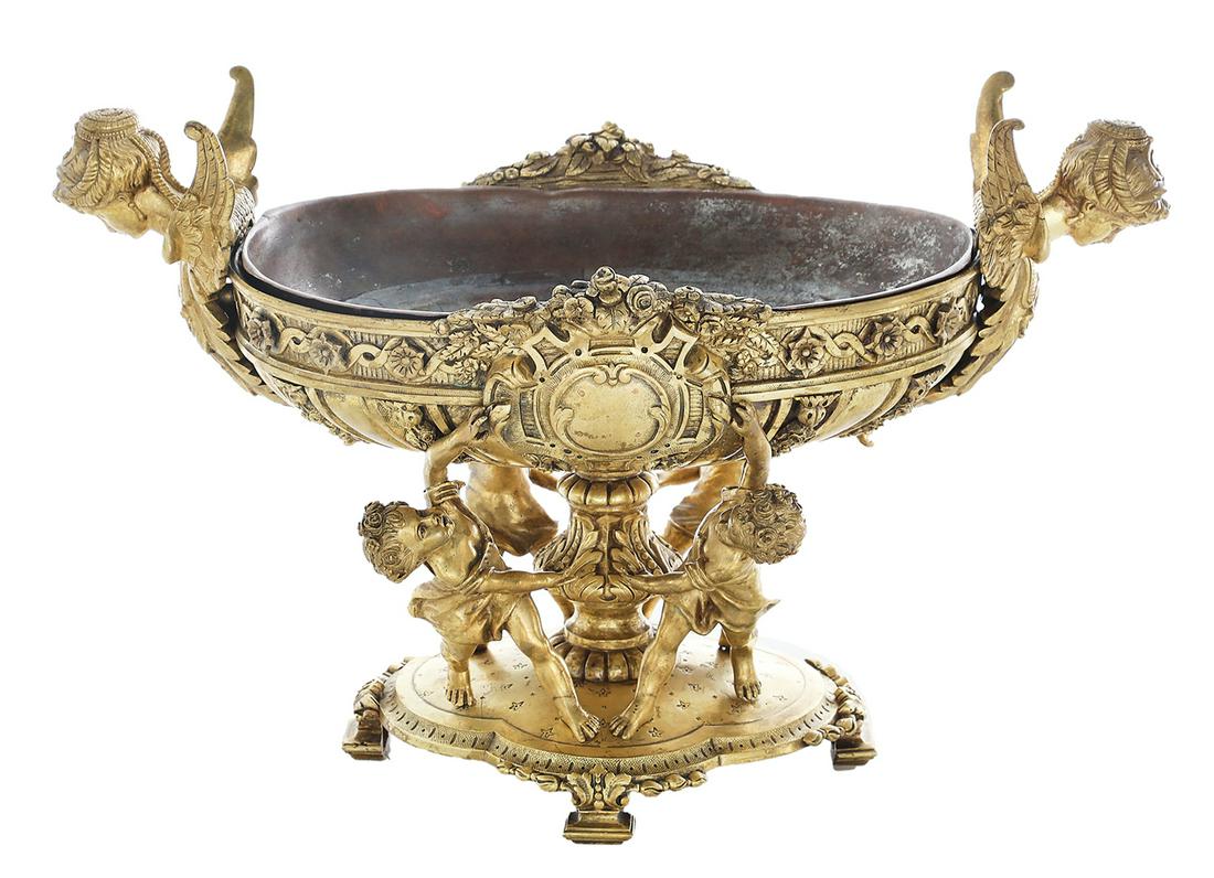 French Gilded Age Gilt-Bronze Centerpiece: French Gilded Age Gilt-Bronze Centerpiece of Baroque Inspiration fourth quarter 19th century, the oval bowl supported by four putti in neoclassical dress, standing on a footed bronze platform, decorat